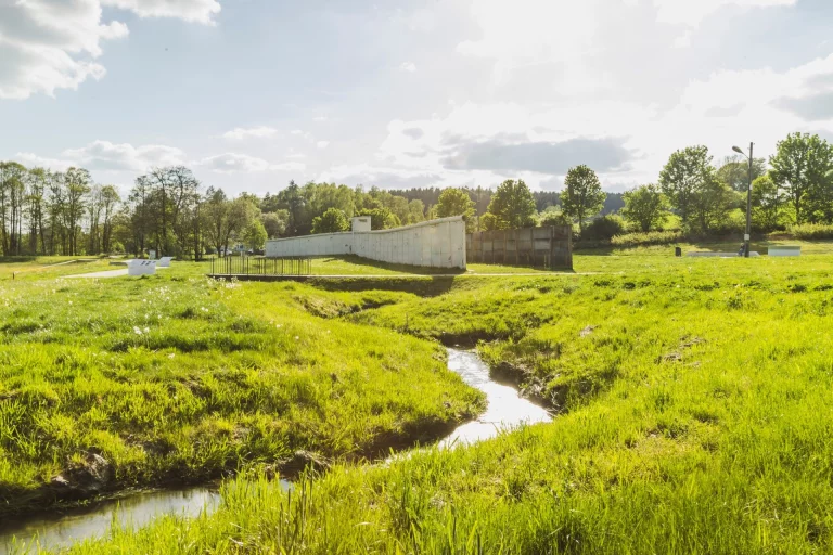 Grünfläche mit Bach und Betonmauer entlang der ehemaligen innerdeutschen Grenze bei Mödlareuth