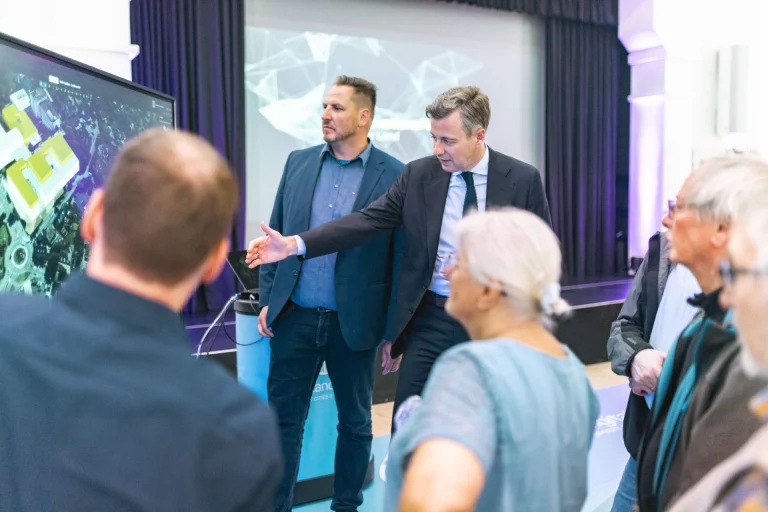 Landrat und Mitarbeiter erläutern Besuchergruppe eine 3D-Stadtkarte des Digitalen Zwillings