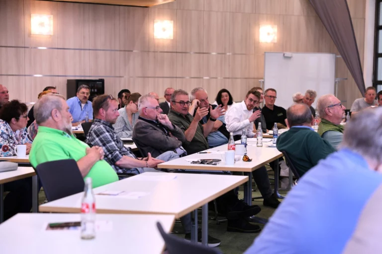 Teilnehmende sitzen an Tischreihen bei einer Diskussion im Rahmen des Waldsymposiums