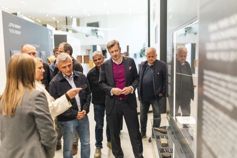 Gruppe von Personen betrachtet Exponate zur Geschichte der Grenzöffnung in einer Ausstellung