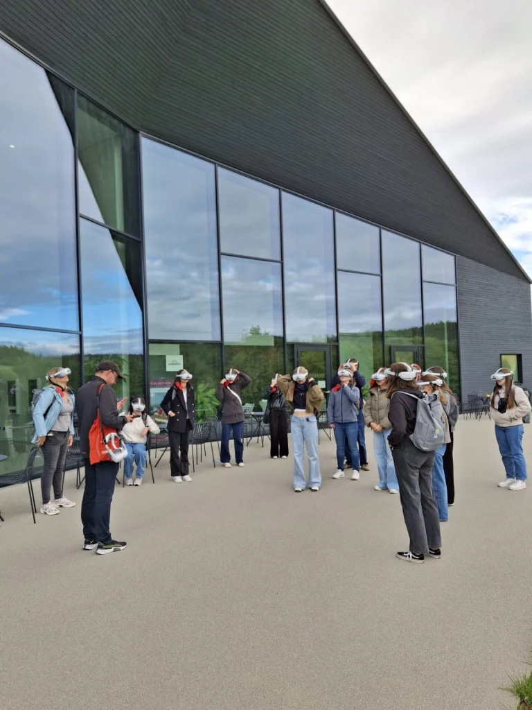 Gruppe mit VR-Brillen vor Glasfassade im Freien bei einem Workshop