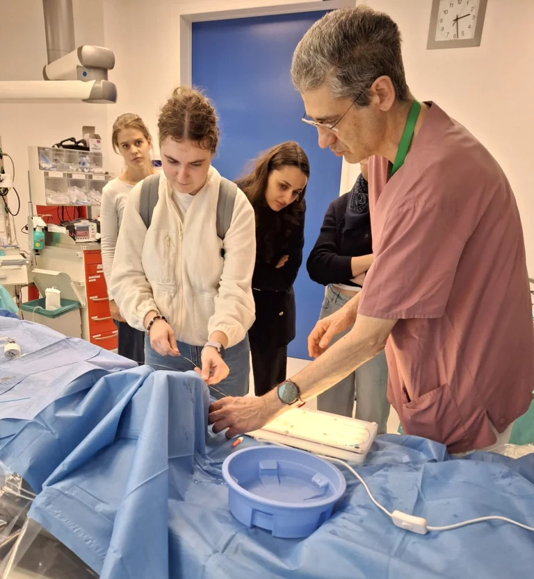 Medizinstudierende beobachten Arzt bei praktischer Übung an OP-Tisch mit sterilem Material