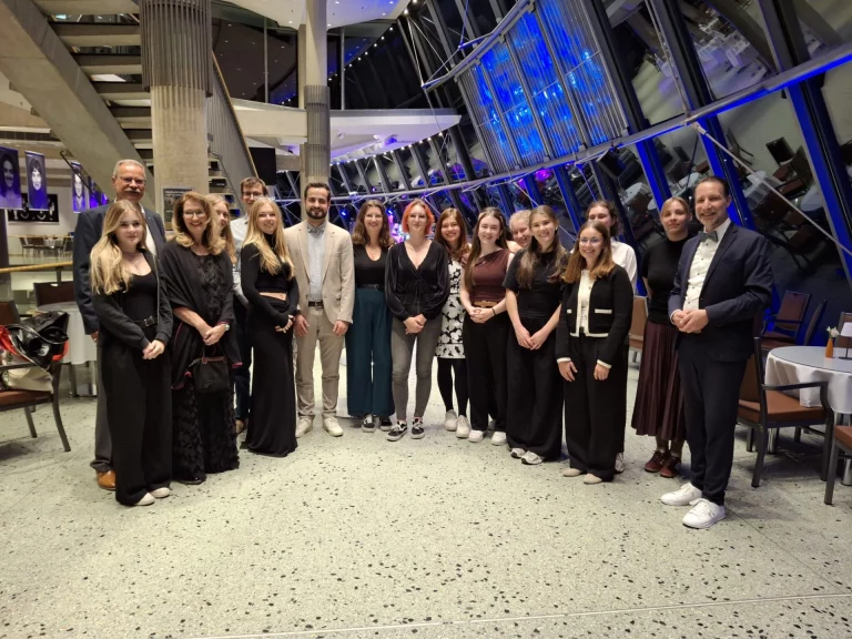 Gruppe von Medizinstudierenden mit Begleitpersonen in festlicher Kleidung in einem Foyer