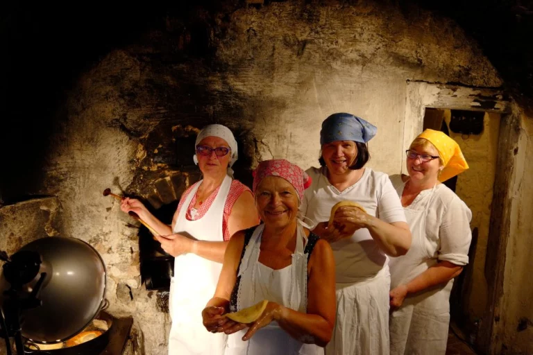 Vier Frauen backen Fladenbrot im historischen Backofen des Bauernhofmuseums