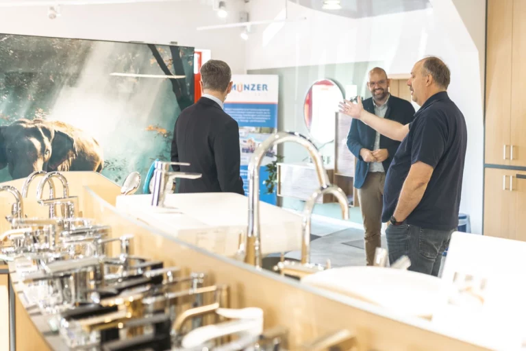 Männer im Gespräch zwischen Ausstellungsstücken für Badarmaturen im Münzer-Showroom