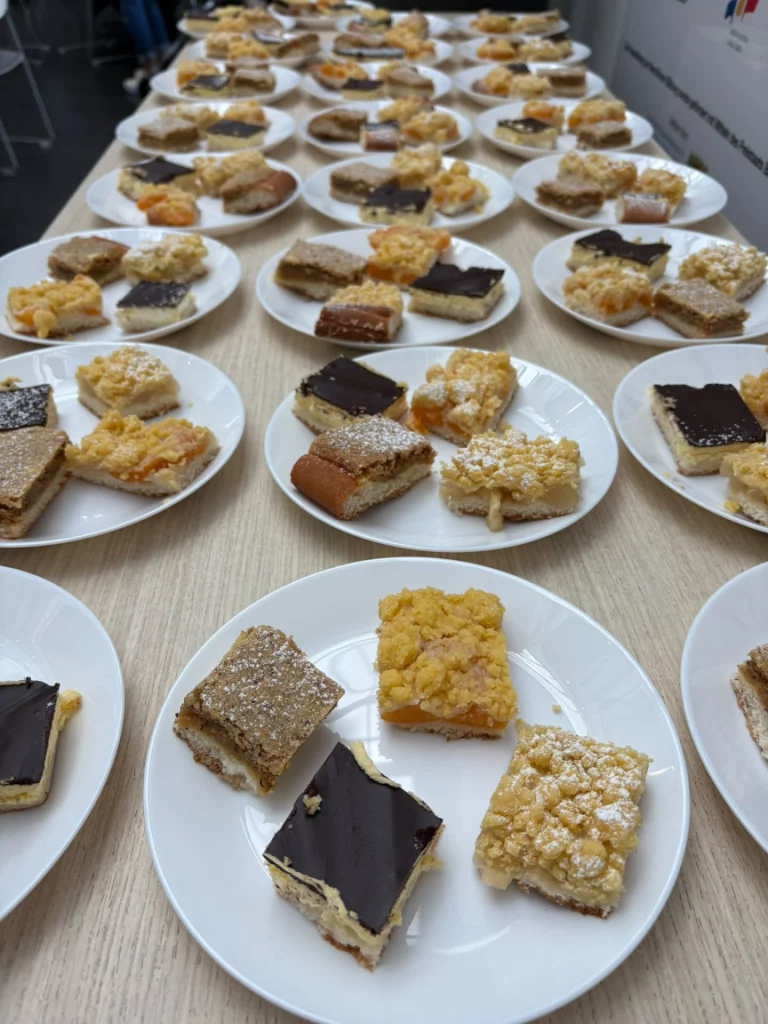 Weiße Teller mit Kuchenstücken, aufgereiht auf einem langen Tisch